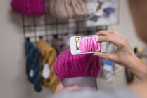 Close-up mulher tirar fotos de fios com telefone celular na loja de alfaiate — Fotografia de Stock