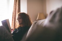 Женщина читает книгу в гостиной — стоковое фото