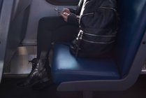 Baixa seção de mulher usando telefone celular enquanto viaja no trem — Fotografia de Stock