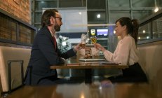 Geschäftsmann und Frau stoßen im Wartebereich am Flughafen mit Sektflöte an — Stockfoto
