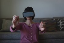 Femme utilisant casque de réalité virtuelle dans le salon à la maison — Photo de stock