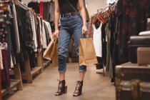 Sección baja de la chica de pie con bolsas de compras en el centro comercial - foto de stock