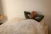 Задумчивый пожилой человек отдыхает в спальне дома — стоковое фото