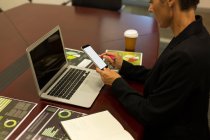 Reife Geschäftsfrau nutzt Handy am Schreibtisch im Büro — Stockfoto
