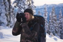 Femme photographiant avec un appareil photo dans la neige par une journée ensoleillée — Photo de stock
