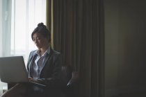 Geschäftsfrau sitzt mit Laptop auf Sessel im Hotelzimmer — Stockfoto