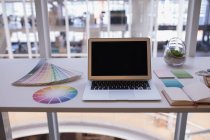 Laptop y muestra de color en el escritorio en la oficina - foto de stock