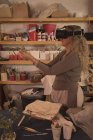 Alfarero femenino usando auriculares de realidad virtual en casa - foto de stock