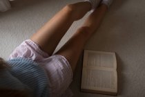 Seção média de mulher sentada com livro em casa . — Fotografia de Stock
