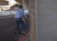 Вид ззаду людини, що їде на велосипеді на вулиці — стокове фото