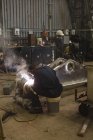 Rear view of welder repairing metal frame in workshop — Stock Photo