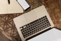 Vista superior do laptop com telefone celular e diário na mesa no café — Fotografia de Stock