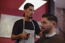 Man getting his hair trimmed with trimmer at barbershop — Stock Photo