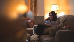 Femmina vlogger seduto sul divano durante l'utilizzo del computer portatile a casa — Foto stock