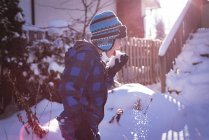 Bonito menino lambendo neve durante o inverno — Fotografia de Stock
