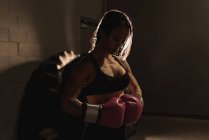 Entschlossene Frau steht mit Boxhandschuhen im Fitnessstudio — Stockfoto