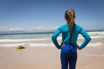 Vista trasera de la chica mirando a su hermana mientras surfeaba en el mar - foto de stock