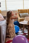 Niedliche Mädchen bläst ein Partyhorn in Wohnzimmer zu Hause — Stockfoto