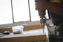 Плотник сверлит деревянную доску с машиной в мастерской — стоковое фото