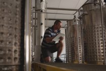 Чоловічий працівник відзначає тиск винокурні в кишені на заводі — стокове фото