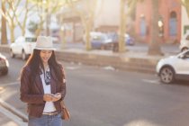 Young woman using mobile phone in city street — Stock Photo