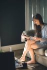 Mujer leyendo revista en sala de estar en casa - foto de stock