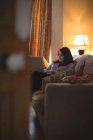 Жіночий відеоблогер сидить на дивані, використовуючи ноутбук вдома — стокове фото