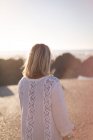 Rear view of blonde woman standing at beach in soft light. — Stock Photo