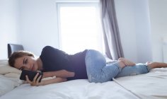 Mulher usando telefone celular no quarto em casa — Fotografia de Stock