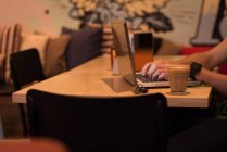 Крупный план мужской руки с помощью ноутбука в кафе . — стоковое фото