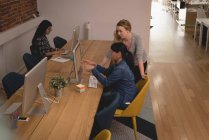 Женщины-руководители обсуждают за компьютером в креативном офисе — стоковое фото