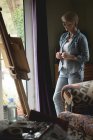 Женщина-художник наблюдает картину на холсте дома — стоковое фото
