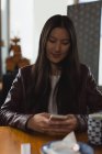 Junge Frau benutzt Handy in Restaurant — Stockfoto