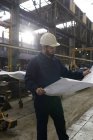 Technicien à la recherche de plans dans l'industrie métallurgique — Photo de stock
