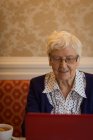 Donna anziana che utilizza il computer portatile a casa — Foto stock