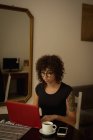 Mulher usando laptop enquanto toma café em casa — Fotografia de Stock