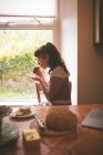 Вид сбоку на женщину, пьющую чай дома — стоковое фото