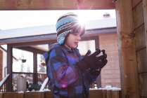 Lindo chico sosteniendo bola de nieve durante el invierno - foto de stock