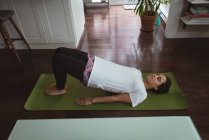 Jeune femme effectuant du yoga sur tapis de yoga à la maison — Photo de stock