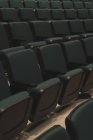 Filas vacías de asientos negros en el teatro . - foto de stock