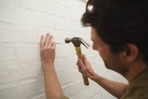 Close-up de carpinteiro masculino martelando unha na parede — Fotografia de Stock