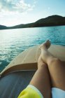 Baixa seção de homem relaxante em um barco em um lago — Fotografia de Stock