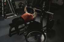 Handicapped man doing chest workout on bench press with barbell in gym — Stock Photo