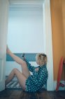 Женщина делает селфи с мобильным телефоном возле двери дома — стоковое фото