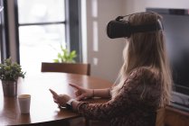 Executivo feminino usando fone de ouvido de realidade virtual com tablet digital de vidro no escritório — Fotografia de Stock