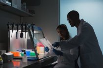 Cientistas discutindo sobre prancheta em laboratório — Fotografia de Stock