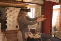 Alfarero femenino usando auriculares de realidad virtual en casa - foto de stock