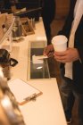 Partie médiane de l'homme effectuant le paiement NFC dans le café — Photo de stock