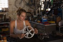 Female mechanic holding crank set and crank arm in workshop — Stock Photo