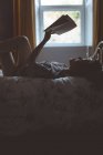 Donna che legge un libro in camera da letto a casa — Foto stock